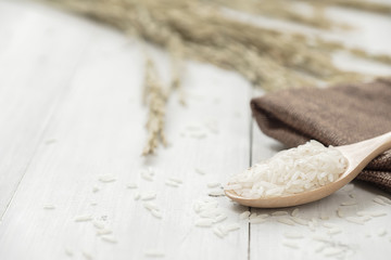 Wooden spoon filled with rice placed on wooden background.