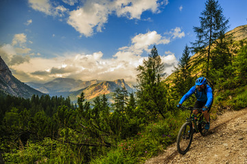 Tourist cycling in Cortina d'Ampezzo, stunning rocky mountains on the background. Man riding MTB enduro flow trail. South Tyrol province of Italy, Dolomites.