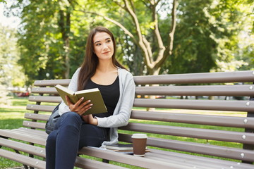 Young woman reading book in park copy space