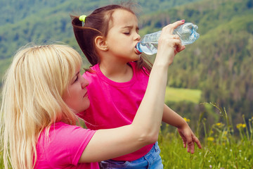 Mother and daughter drink water in the mountains