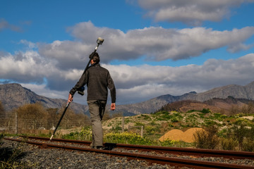A land surveyor walking with a trimble gps rover survey equipment wih dark clouds behind him