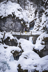 Young women hiking through snowy gorge Baerenschuetzklamm with frozen waterfalls