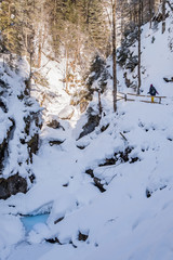 Young women hiking through snowy gorge Baerenschuetzklamm with frozen waterfalls