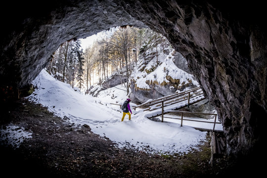 Women hiking from cave to bridge in snowy gorge Bearenschuetzklamm