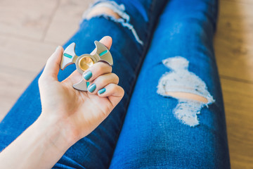 Girl teenager in holey jeans holds in hands and plays with spinner