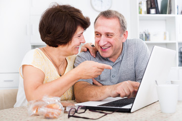 Mature man and woman looking at laptop