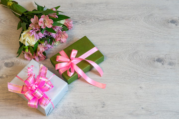 Colorful bouquet of roses, chrysanthemum and alstroemeria flowers with gift boxes on wooden background