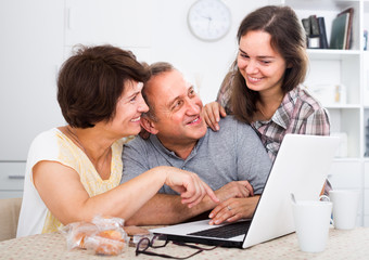 senior couple and daughter with laptop at home.