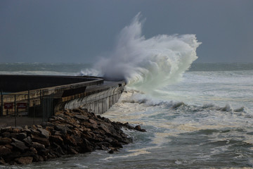 Big storm waves reach a breakwater structure in a pier in the Atlantic coastline. Cascais Portugal