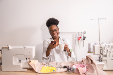 Laughing african seamstress sewing in tailor studio