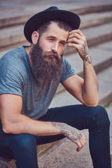 A handsome hipster male with a stylish beard with a tattoo on hi