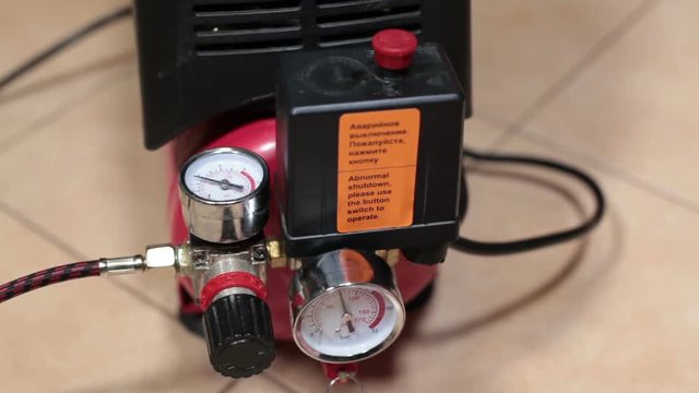 Bleeding of air from the receiver and automatic activation of the compressor, close up view at hand and manometer