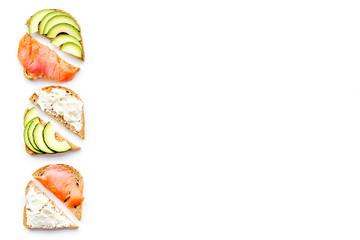 Healthy lunch with mini sandwiches cheese, fish and avocado on white background top view space for text