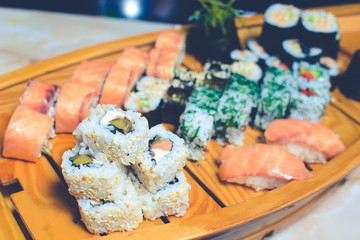 many kinds of sushi on a wooden stand in the form of a ship