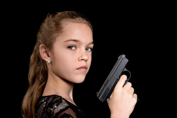 Close-up portrait of a young girl with a gun in her hand isolated on a black background