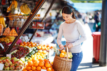 Young female buys fruits on street market.