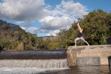 female performing yoga pose with scenic mountain and river background