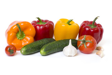 Red yellow and orange peppers with tomatoes on a white background. Cucumbers with colorful peppers in composition on a white background..