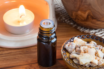 A bottle of styrax benzoin essential oil with benzoin resin and an aroma lamp