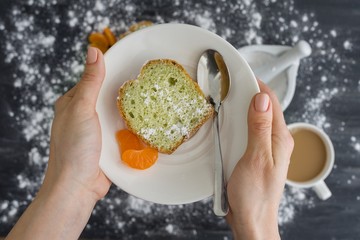 Mint cake sprinkled with powdered sugar on dark surface with fresh oranges mandarins