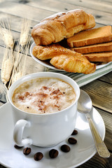 Traditional Italian breakfast with cappuccino and croissants on a rustic wooden table