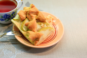 Apple pie piece and cup of tea on gray table background.