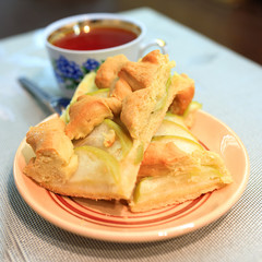 Apple pie piece and cup of tea on gray table background.