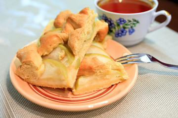 Apple pie piece and cup of tea on gray table background.