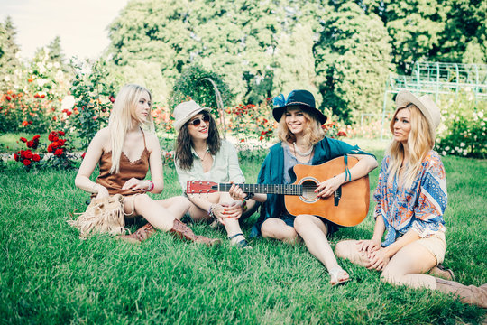 Summer holidays, vacation, travel and people concept - smiling young hippie women with guitar playing music. Funny time for the best friends. Lifestyle. Boho style.