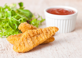 Fried chicken dippers on chopping board with sauce
