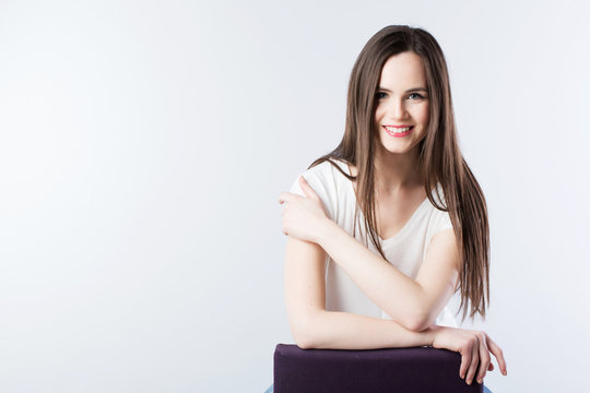 Fototapeta Young beautiful smiling woman with long straight hair on a gray.