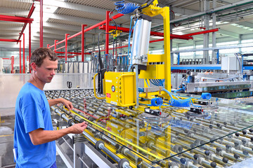 Jugenedlicher Arbeiter in einer Fabrik zur Herstellung von Glasscheiben (Fensterglas, Flachglas) -...
