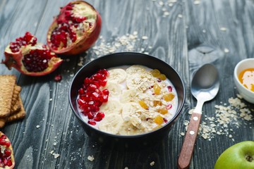 Healthy and tasty dieting concept. Delicious low calorie yoghurt smoothie bowl with banana slices, pomegranate and raisins for breakfast