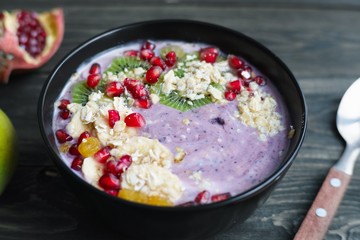 Healthy and tasty dieting concept. Delicious low calorie oatmeal and yoghurt smoothie bowl with fruit slices and pomegranate for breakfast