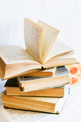 a stack of old battered books, and upstairs, an open book on a white background, copyspace
