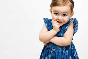 Close up of a curious toddler child with arms folded and finger on cheek