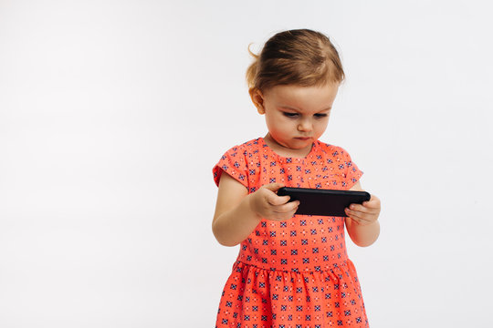 Small child looking at cell phone, isolated on white studio background