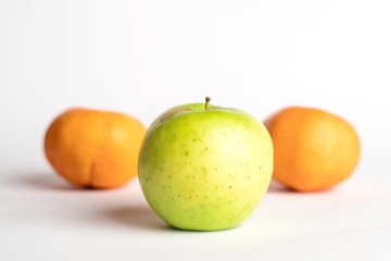 Green juicy apple with 2 mandarins on a white background with copyspace