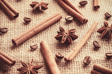 Coffee beans and cinnamon sticks with anise stars organized separately on sackcloth