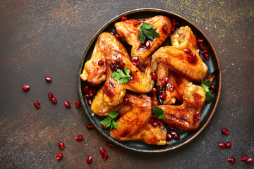 Grilled chicken wings in a honey orange glaze with pomegranate seeds.Top view with copy space.
