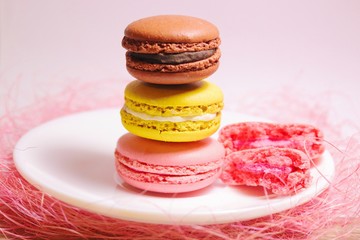 Macaroons stack of different colors standing on white plate. Front view.
