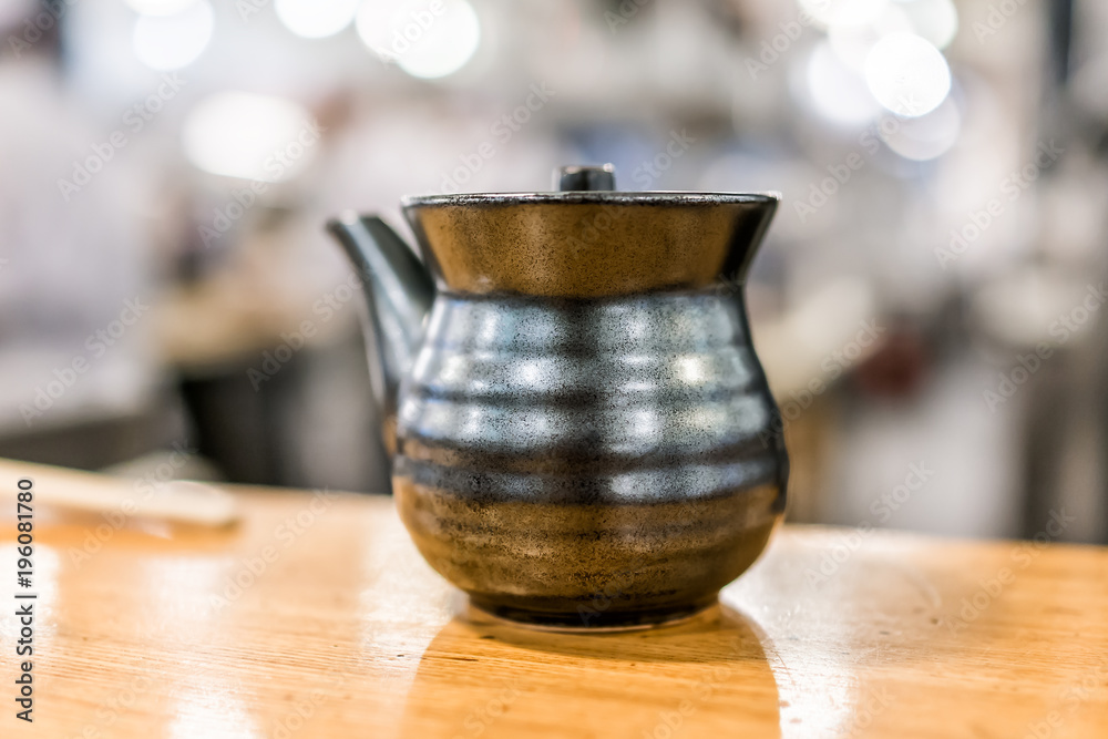 Wall mural Macro closeup of traditional black clay Japanese teapot pot cermaic porcelain on wooden table in cafe restaurant isolated