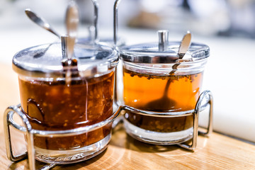 Macro closeup of Japanese asian orange sweet sauces dipping soy for sushi, glass containers on table bar counter with spoons garnishes