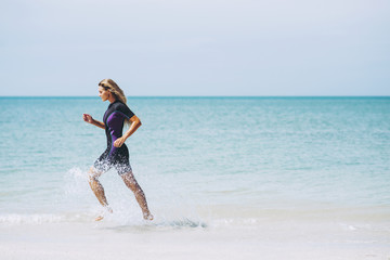 Beautiful woman in wetsuit on the idyllic beach