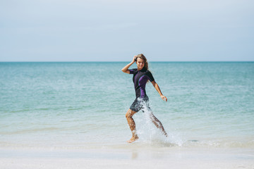 Beautiful woman in wetsuit on the idyllic beach