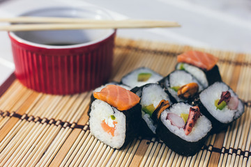 A sushi set with a sauce bowl and bamboo sticks on the bamboo background