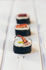 Sushi rolls with octopus on the white wooden background