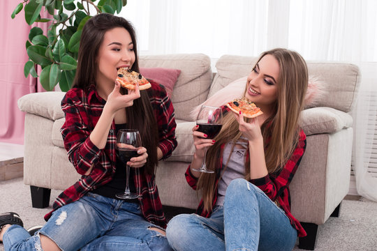 Best friend is always around! Closeup photo of young mirthful good-looking ladies tasting cheese Italian pizza with red wine.