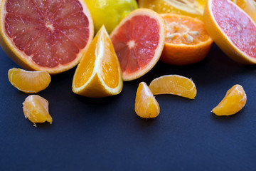 Colored Citrus fruits on a dark blue background. Slices of citrus and peel. Citrus reticulata. Citrus paradisi. Citrus limon. Citrus sinensis.
