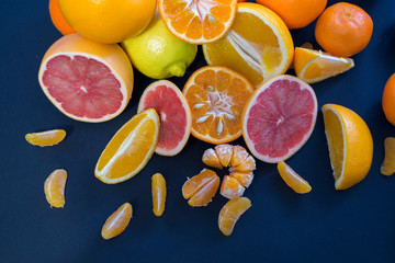 Colored Citrus fruits on a dark blue background. Slices of citrus and peel. Citrus reticulata. Citrus paradisi. Citrus limon. Citrus sinensis.
